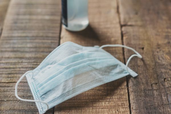 Mask and sanitizer on a wooden table. They are part of our lives now.